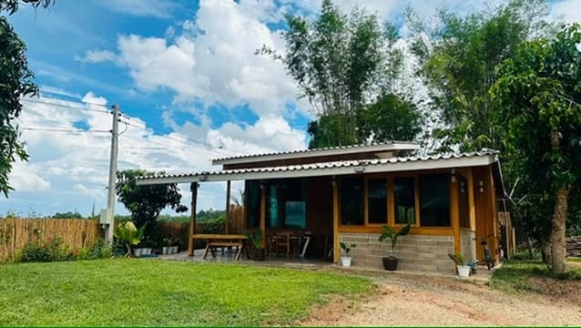 A teak cabin under wide blue sky, the field stretching out to distant trees.