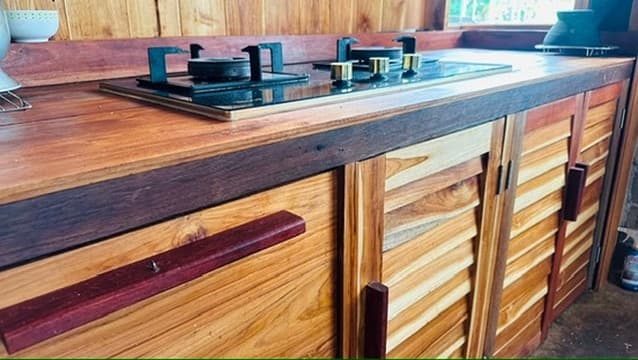 A worn teak kitchen counter with a small gas stove.