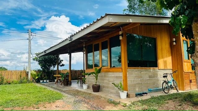The side of a teak cabin, blue sky and bamboo just beyond.