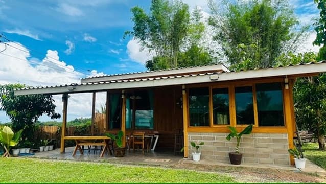 Hidden Field — a teak cabin set against bamboo and distant hills.