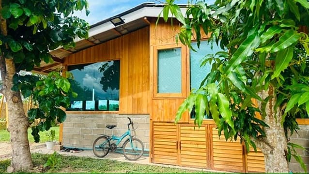 Field Room — a small teak cabin under afternoon light, bicycle resting against the wall.