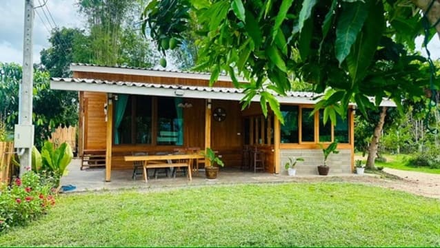 Mist House — a teak cabin under a mango tree, with a long wooden porch.